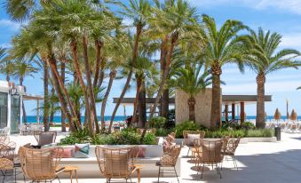 a beachfront resort with palm trees , chairs , and couches set up for guests to enjoy the view at Hotel Cap Negret