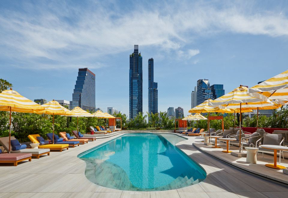 There is a rooftop area in front of the hotel with a swimming pool, as well as chairs and umbrellas at The Standard, Bangkok Mahanakhon