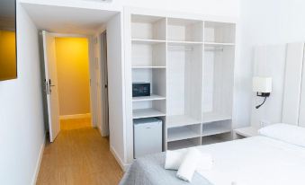 a white bedroom with a bed , a refrigerator , and a closet , as well as a door leading to another room at Hotel Son Vilar