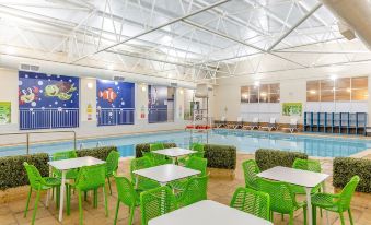a large indoor swimming pool surrounded by tables and chairs , providing a relaxing environment for guests at North Devon Resort