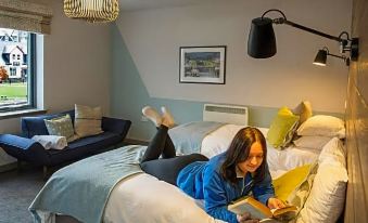 a young woman is lying on a bed reading a book in a cozy room at Lock Chambers, Caledonian Canal Centre