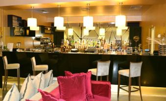 a bar with a pink couch and several chairs , along with several bottles and glasses on the counter at Cosmopolitan Hotel