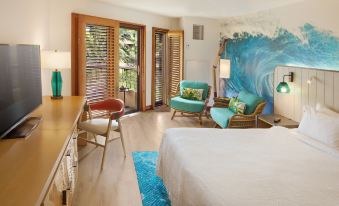 a modern bedroom with wooden floors , white walls , and blue furniture , including a bed , chairs , and table at Sheraton Kauai Coconut Beach Resort