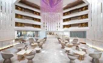 a modern hotel lobby with white marble floors , seating arrangements , and a large chandelier hanging from the ceiling at JW Marriott Cannes
