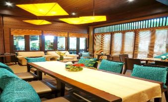 a large dining room with a long wooden table and multiple chairs , surrounded by windows and wooden walls at Kuiburi Hotel & Resort