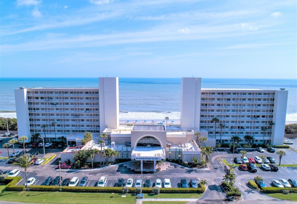 an aerial view of a large hotel with a parking lot and ocean in the background at DoubleTree Suites by Hilton Melbourne Beach Oceanfront