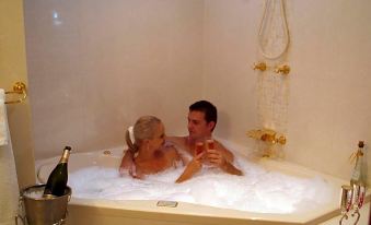 a man and a woman are sitting in a bathtub filled with bubbles , holding wine glasses at Reid's Place