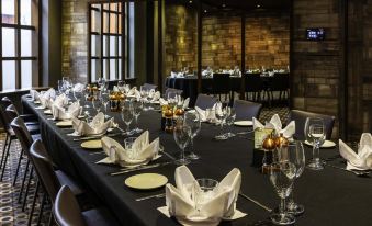 a long dining table set with multiple place settings , including wine glasses , forks , knives , and spoons at Novotel Leeds Centre