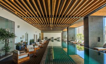 a large indoor swimming pool with a wooden ceiling and lounge chairs surrounding it , creating a relaxing atmosphere at Hyatt Regency Andares Guadalajara
