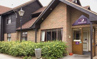 a brick building with a purple sign and a bush of yellow flowers in front of it at Sandhurst