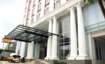 a large white building with columns and a glass entrance , possibly a hotel or an office building at Savero Hotel Depok