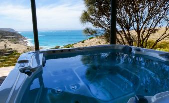 a hot tub with a glass roof , situated on a balcony overlooking the ocean and trees at Sea Dragon Kangaroo Island