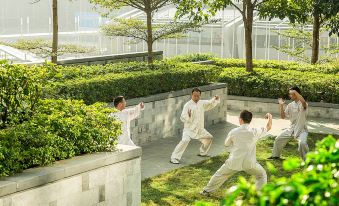 A group of people is practicing yoga in the park, with young men standing behind them at Four Seasons Hotel Shenzhen