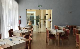 a large , empty dining room with multiple tables and chairs , set for a meal , and a doorway leading to another room at Hotel Francis