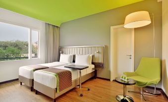 a modern hotel room with two beds , wooden floors , and green walls , as well as a small dining area at Park Inn by Radisson New Delhi Lajpat Nagar