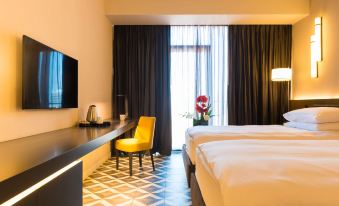 a hotel room with a king - sized bed , a tv , and a dining table with chairs at Radisson Hotel, Dakar Diamniadio