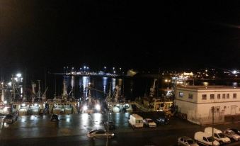 a night view of a harbor with boats and cars , including one on the left side at Tara Hotel