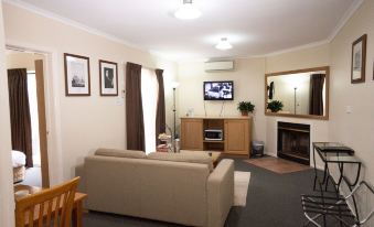 a living room with a couch , coffee table , and television is shown in this image at Admiralty Inn