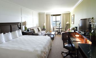 a hotel room with a large bed , couch , desk , and other furniture , including chairs and a desk at Riverside Hotel