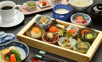 a wooden tray filled with various japanese dishes , including sushi and soup , placed on a dining table at Hotel Metropolitan Yamagata