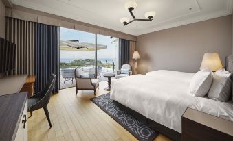 a spacious bedroom with a large bed , a dining table , chairs , and a balcony overlooking the ocean at Kawana Hotel