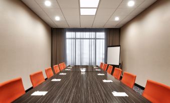 a conference room with a long wooden table , orange chairs , and a whiteboard in the background at Fairfield Inn & Suites Houston League City