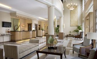 a luxurious hotel lobby with a large reception desk , comfortable seating , and a chandelier hanging from the ceiling at Hotel Venezia