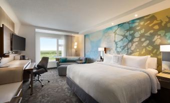 a hotel room with a large bed , a couch , and a painting on the wall at Courtyard Oshawa