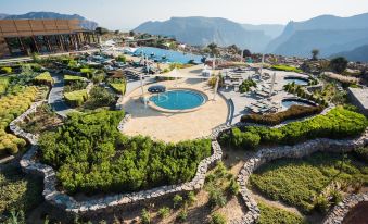 a resort with a large pool surrounded by lush greenery , mountains in the background , and mountains in the distance at Anantara Al Jabal Al Akhdar Resort