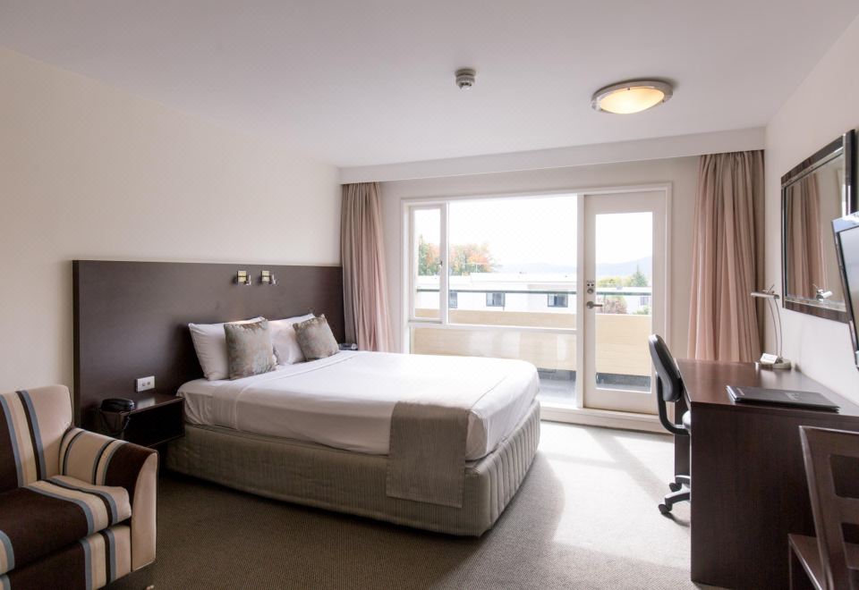 a modern hotel room with a large bed , a desk , and a window overlooking the city at St Ives Apartments