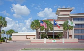 a large building with american and texas flags flying in front of it , surrounded by palm trees at Holiday Home Park Central Port Arthur