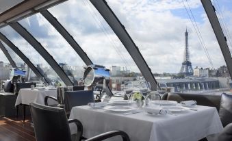 a dining room with a view of the eiffel tower , a table set for two , and chairs at Hotel the Peninsula Paris