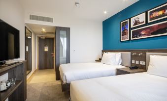a modern hotel room with two beds , white bedding , and blue walls , along with a small office area at Hampton by Hilton Stockton on Tees
