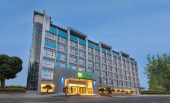 The hotel is illuminated at night, providing an exterior view from across a parking area at Holiday Inn Express Xiamen Tongan
