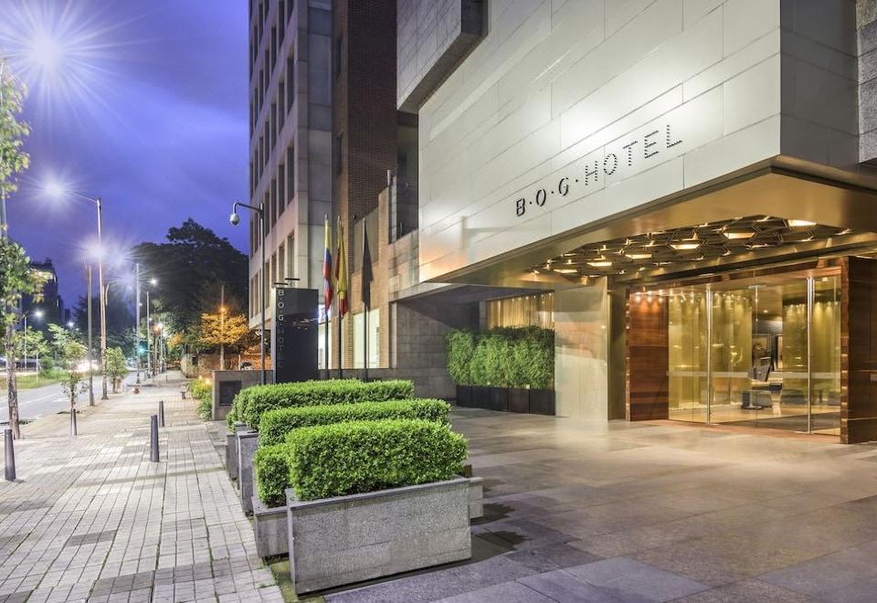 "a modern building with the name "" 8 0 6 hotel "" on it , surrounded by greenery and lit up at night" at Bog Hotel