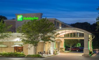 a holiday inn hotel with its name displayed on the building , and cars parked outside at Holiday Inn South Kingstown (Newport Area)