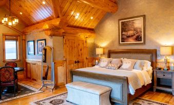 a cozy bedroom with a wooden ceiling , a large bed , and a television mounted on the wall at Coyote Bluff Estate