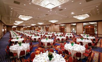 a large banquet hall filled with round tables and chairs , ready for a formal event at Hilton Memphis