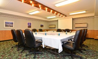 a large conference room with a white tablecloth , multiple chairs , and a projector screen , set up for meetings or presentations at Best Western Plus Longbranch Hotel  Convention Center