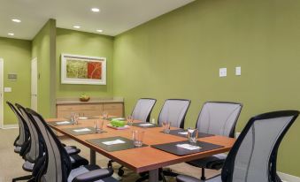 a conference room with a wooden table , chairs , and framed artwork on the wall , ready for meetings or presentations at Home2 Suites by Hilton Canton
