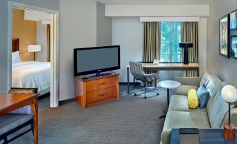 a living room with a flat - screen tv , couch , and dining table in a hotel room at Residence Inn Fort Lauderdale Weston