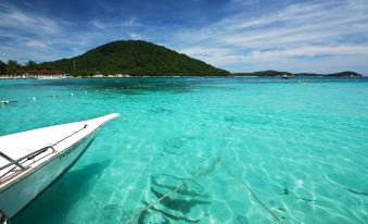 a boat is floating in a clear blue ocean with a mountain in the background at Perhentian Island Resort