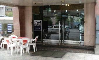 an outdoor dining area with several tables and chairs , as well as a car parked outside the building at Copacabana