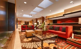 a spacious hotel lobby with red couches , a large table , and potted plants , creating an inviting atmosphere at Wyndham Minneapolis South/Burnsville