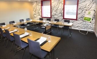 a conference room with wooden tables , chairs , and papers set up for a meeting or presentation at Holiday Inn Salisbury - Stonehenge