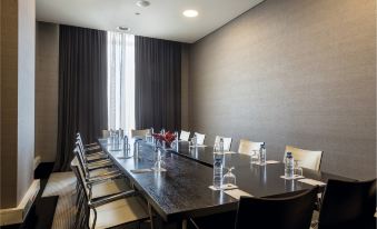 a large conference room with a long wooden table surrounded by chairs , and several water bottles placed on the table at Hotel Baia