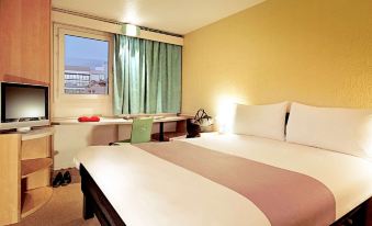 a large bed with a pink and white striped blanket is in a room with a window at Ibis Lagos Ikeja