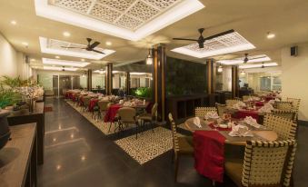 a large , well - lit restaurant with multiple dining tables and chairs arranged for guests to enjoy a meal at Pranaya Boutique Hotel