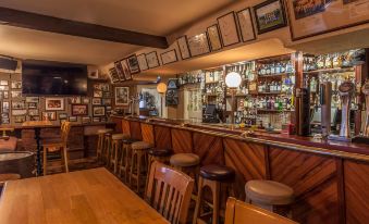 a bar with wooden walls and bar stools , along with framed pictures on the wall at Sandhouse Hotel