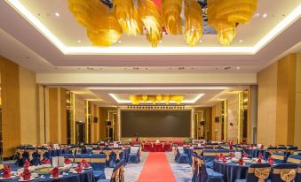 a large banquet hall with red drapes and a stage is set up for an event at Ames Hotel